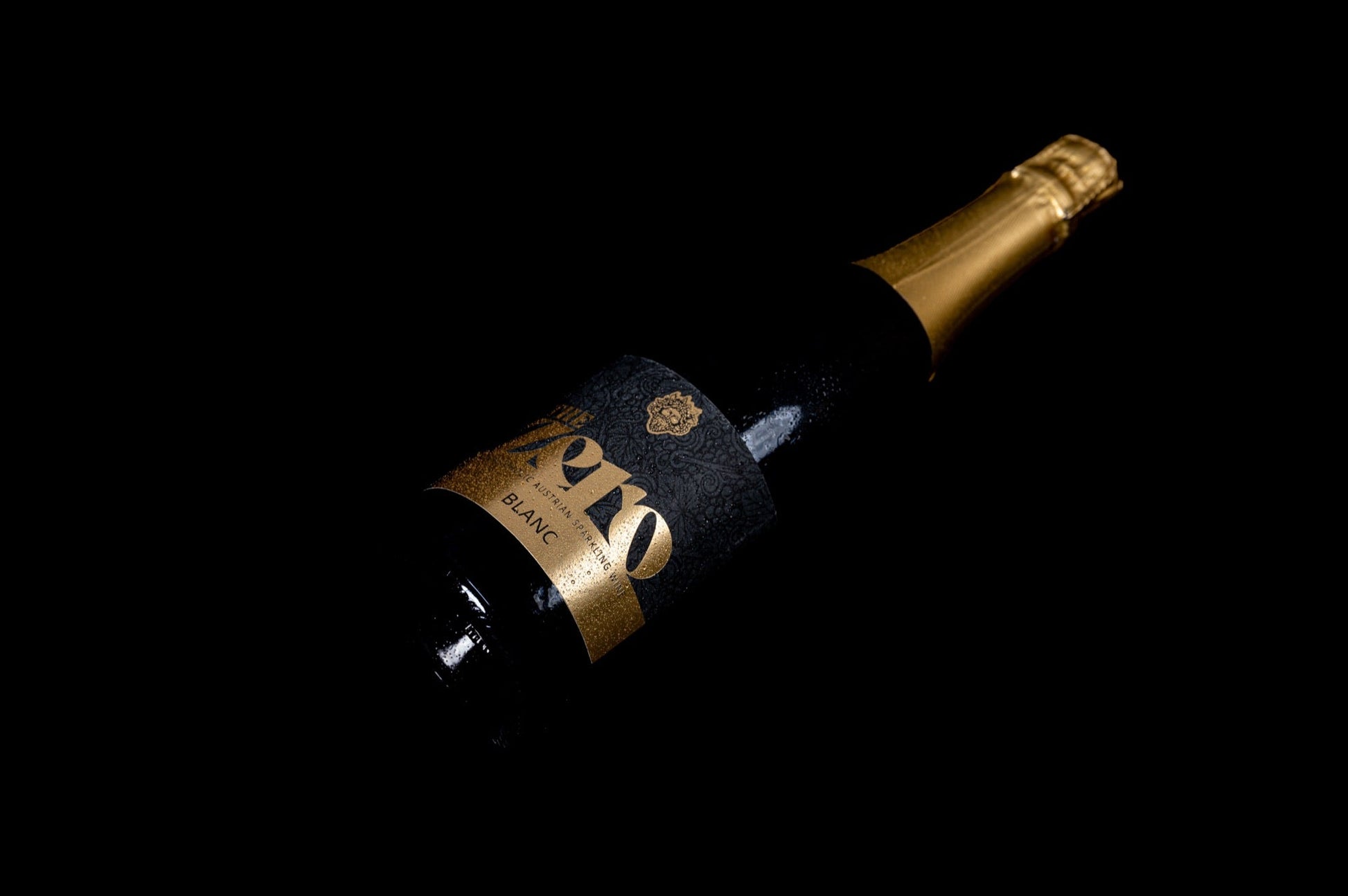 Liggende fles The Zero met goudkleurig etiket tegen een zwarte achtergrond