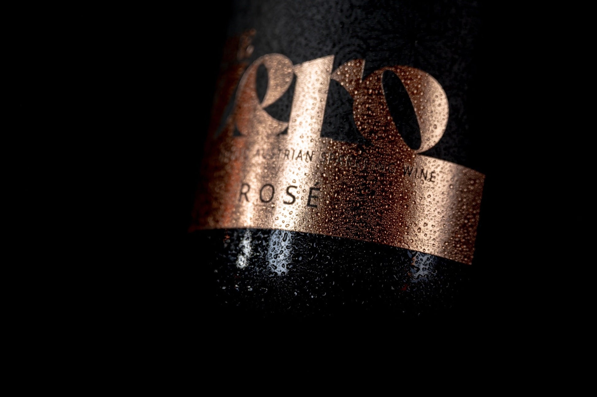 Detail van het koperkleurige etiket van The Zero Sparkling Rosé met condensdruppels